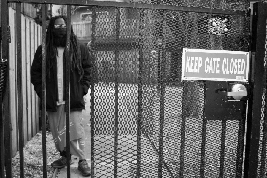 Joseph stands on the opposite side of a gate to the pool area that has been closed since the start of the COVID-19 pandemic on Wednesday, March 10, 2021 in Sacramento, California. Although he is experiencing the most freedom he has had in years, Joseph is still confined to Sacramento County through the ankle monitor on his right foot that only allows him to travel 50 miles from his home. 