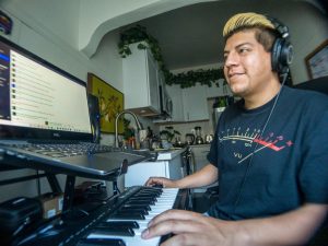 DJ/promoter/music artist Alex Hernandez, 30, has his equipment setup in the kitchen of his studio apartment downtown Sacramento. He records and plays keyboard digitally with software that allows him to plug-in sounds of other instruments. Here, Hernandez is playing with a synthesizer plug-in Saturday, April 10, 2021.  (Robert J Hansen)