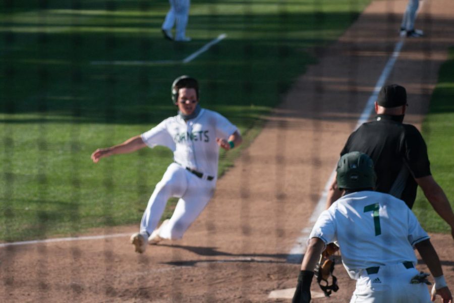 Keith Torres (right) guides teammate Trevor Doyle into the plate during the home game against Stanford University at John Smith Field on Monday, March 29, 2021. Doyle scored the second run in the seventh inning against Stanford University to tie the game.
