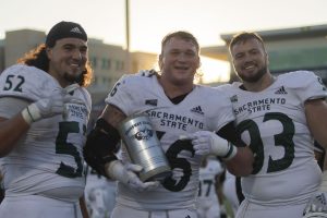 Freshman offensive lineman Ivan Garza (52), defensive linemen Brandon Knott (56) and Tyler Hardeman (93) pose with the Causeway Trophy after winning the Causeway Classic against UC Davis at UC Davis Health Stadium on Nov. 20th, 2021. The Hornets beat the Aggies 27-7 to become undisputed Big Sky Conference champions.