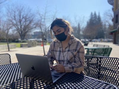 Second-year psychology major Margaret Rocha sits outside the American River Courtyard Market on Thursday, Feb. 10. Rocha said she has concerns over where to get tested for COVID-19 as a new resident in Sacramento. 