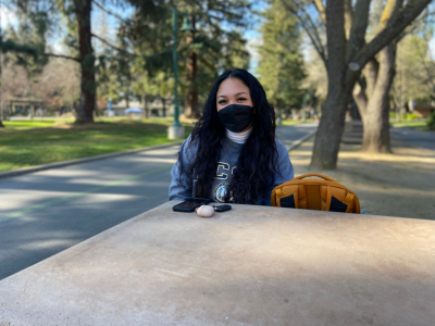 Therese Gatchalian, a third-year pre-nursing major, sits near the library benches on Friday, Feb 18. Gatchalian said she agrees with the campuss continued requirement to wear masks indoors and feels that masks protect students when social distancing in classrooms is impossible. (Photo by Priscilla Garcia-Pargas)

