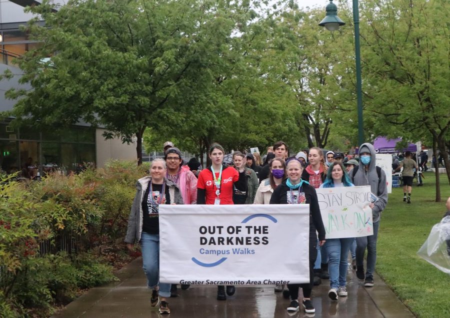 Participants end the “Out of the Darkness” campus walk at The WELL on Thursday, April 14, 2022. A banner was held by participants who led and identified the group.  