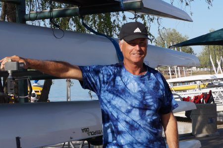 Coach Mike Connors poses on some boats near Lake Natoma on Saturday, April 2, 2022. Connors began rowing in 1979 when he was a high school walk-on at Santa Clara University and has been continuously involved with the sport since. 
