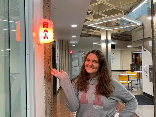 Fourth-year biological and archaeological anthropology major Charlotte Barna poses by the “on air” sign at the KSSU studio in the Sacramento State University Union on Tuesday, April 5, 2022. As a first-semester DJ, Barna hosts a show on Monday mornings where she shares music and personal insight into various songs.