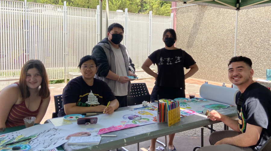 Students take a break in between classes to paint on a long roll of paper in the Kadema Hall Courtyard on Wednesday, April 27, 2022. Professors would stop by and draw as well or just look at the drawings the students had made. 