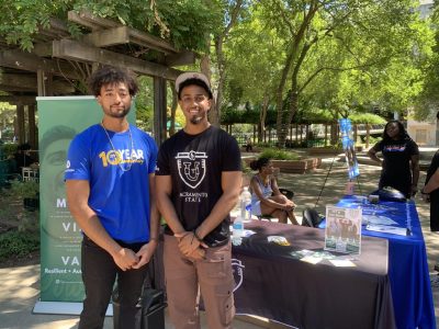 Student clubs and organizations gather on campus to celebrate the first two weeks of school with Club Days. Fourth-year human resources majors Deion Perry (left) and Anil Benoit (right) pose in front of the “Improve Your Tomorrow University” table in the library quad on Wednesday Aug. 31, 2022. 