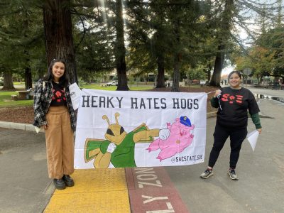 (R-L) Jenny Ruiz and Lillyana Sanchez, both fourth-year ethnic studies majors, hold a   banner near the Sac State Library quad on Wednesday, Nov. 9, 2022. “We wanted something with a little bit of a shock factor,” Sanchez said. “Other SQE chapters at other campuses have more radical artwork, so this is pretty tame in my opinion.”