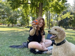 Biology major Haley Anderson, one out of the many students on campus with a service dog, smiles while accompanied by her service dog. She plays fetch after class with her service dog to end her day on Tuesday Sept.27, 2022. 