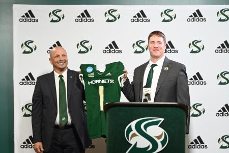 The newest Sac State head football coach Andy Thompson holds up a Hornet jersey with Athletic Director Mark Orr Thursday, Dec. 15, 2022, in the Welcome Center at Sacramento State. Thompson was the defensive coordinator for the past four years under former head coach Troy Taylor until his announced promotion Thursday.