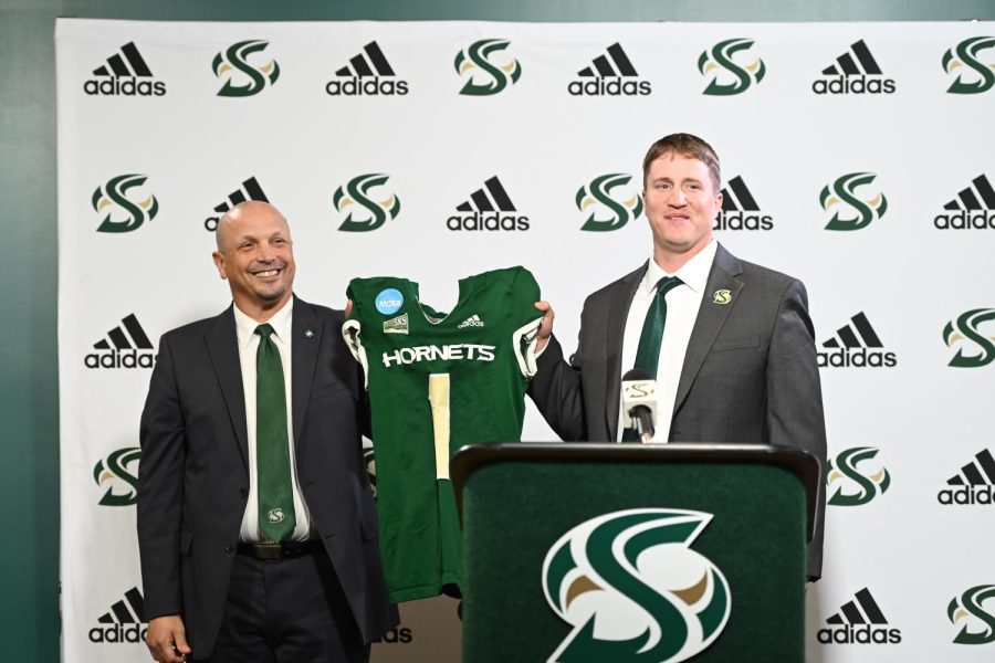 The+newest+Sac+State+head+football+coach+Andy+Thompson+holds+up+a+Hornet+jersey+with+Athletic+Director+Mark+Orr+Thursday%2C+Dec.+15%2C+2022%2C+in+the+Welcome+Center+at+Sacramento+State.+Thompson+was+the+defensive+coordinator+for+the+past+four+years+under+former+head+coach+Troy+Taylor+until+his+announced+promotion+Thursday.