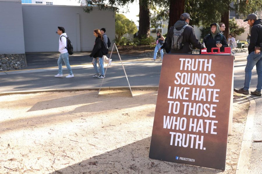 A+sign+from+Project+Truth+claiming+their+truth+sounds+like+hate+to+others.+One+student+is+debating+with+two+members+of+the+group+behind+the+sign.%0A