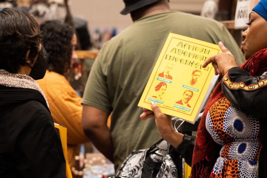 A vendor shows an attendee educational literature about African American Inventors on Friday Feb. 24, 2023. In addition to the market, the Sacramento Black Expo features various organizations aimed at bringing awareness to the public about Black history and community development.
