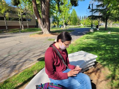 Sandra Pantoja, a fourth-year history major, sits between Tahoe Hall and The WELL Wednesday, April 19, 2023. Pantoja said she always carries her belongings with her so they won’t get stolen.