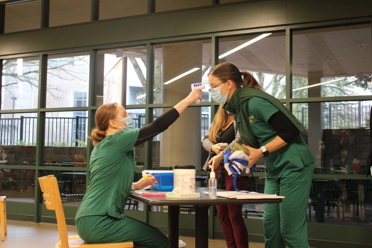 A nursing student checks another student’s body temperature during the pandemic before letting her enter the Brown Bag room in the University Union Thursday, Jan. 28, 2021. Now, Sac State faces another surge as COVID-19 numbers rise throughout the community. 