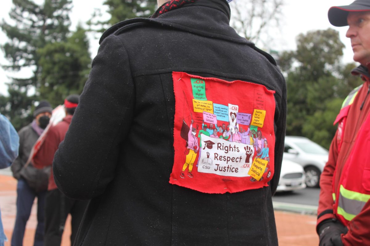 California Faculty Association President Anne Luna protests with colleagues at the west Sac State entrance Jan. 22, 2024. Luna sported a thrifted coat with a patch added to the back with the words, “Rights, Respect and Justice” 