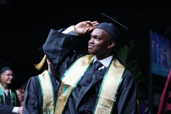 A graduate salutes to family in a crowded Golden 1 Center during their commencement for Sac State, May 23, 2023. A goal of the Black Student Success Task Force is to offer numerous resources to increase the amount of Black students earning a degree. 