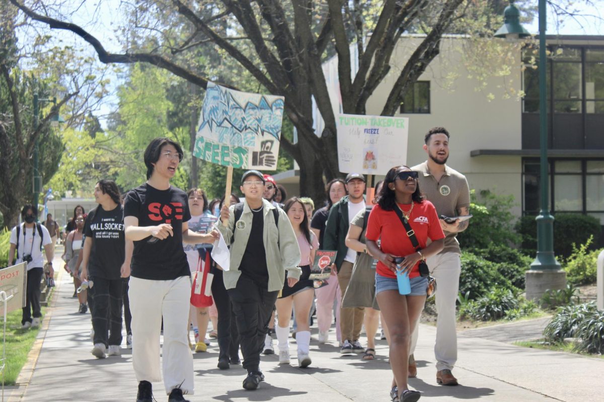 Michael Lee Chang, estudiante en prácticas de Estudiantes para Educación de Calidad (SQE) dirigiendo manifestantes hacia Sacramento Hall el miércoles 10 de abril del 2024. Manifestantes se reunieron afuera del edificio antes de dejar sus folletos en la oficina del Presidente Luke Wood.