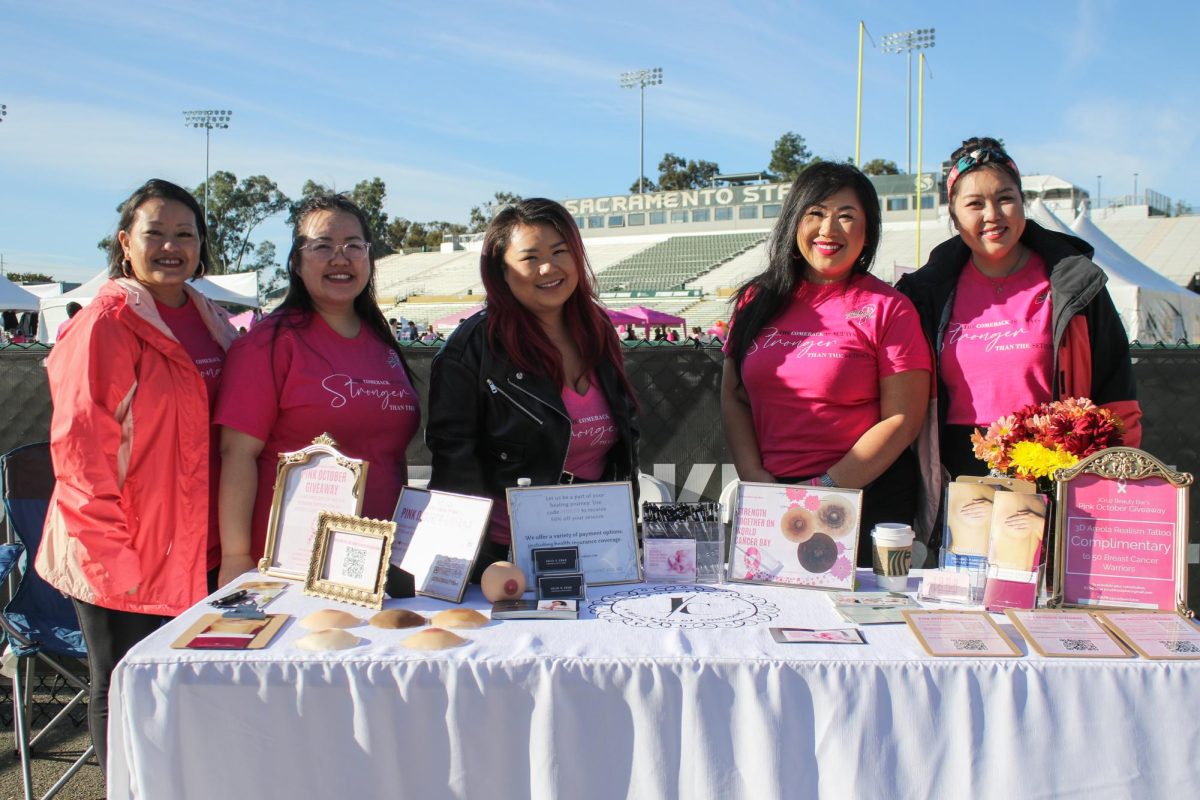 Julie Cruz (second from right) stands behind her paramedical tattoo studio table Sunday, Oct. 27, 2024. Cruz was promoting 3D areola tattoos for those who have undergone mastectomies.