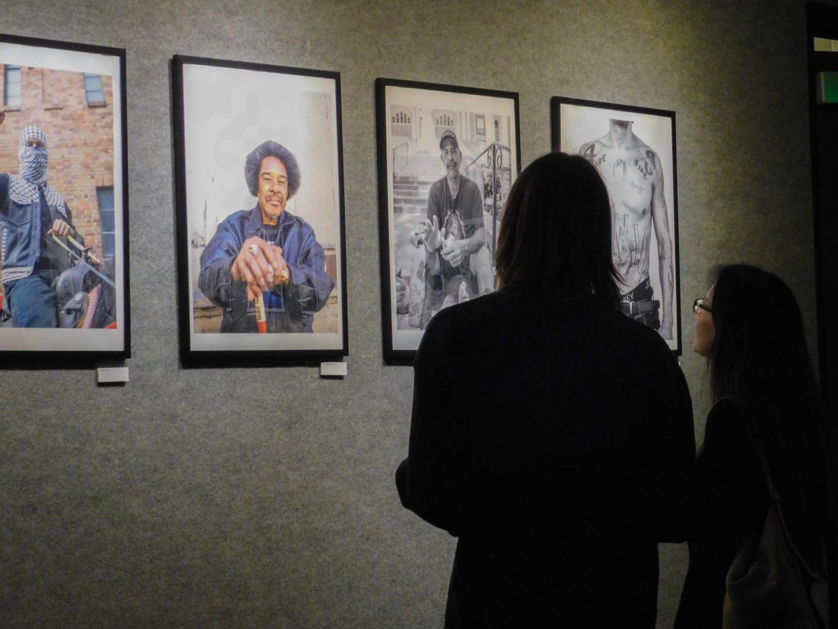 Two gallery attendees view four portrait pieces in the University Union Gallery Thursday, Sept. 26, 2024. Guests were able to attend a special opening ceremony of the “For the People” photo gallery.