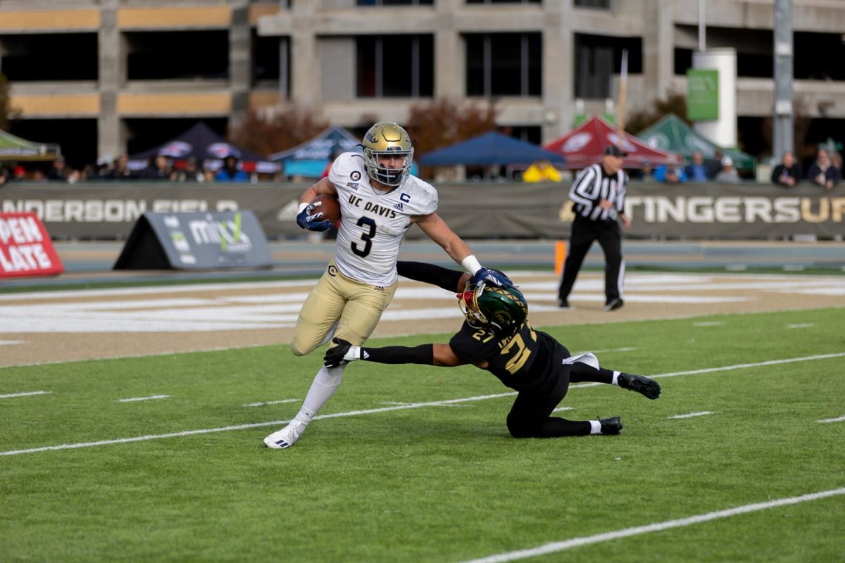 UC Davis running back Lan Larison stiff arms a Sacramento State defender in the Causeway Classic Saturday Nov. 23, 2024. The Hornets lost 42-39.