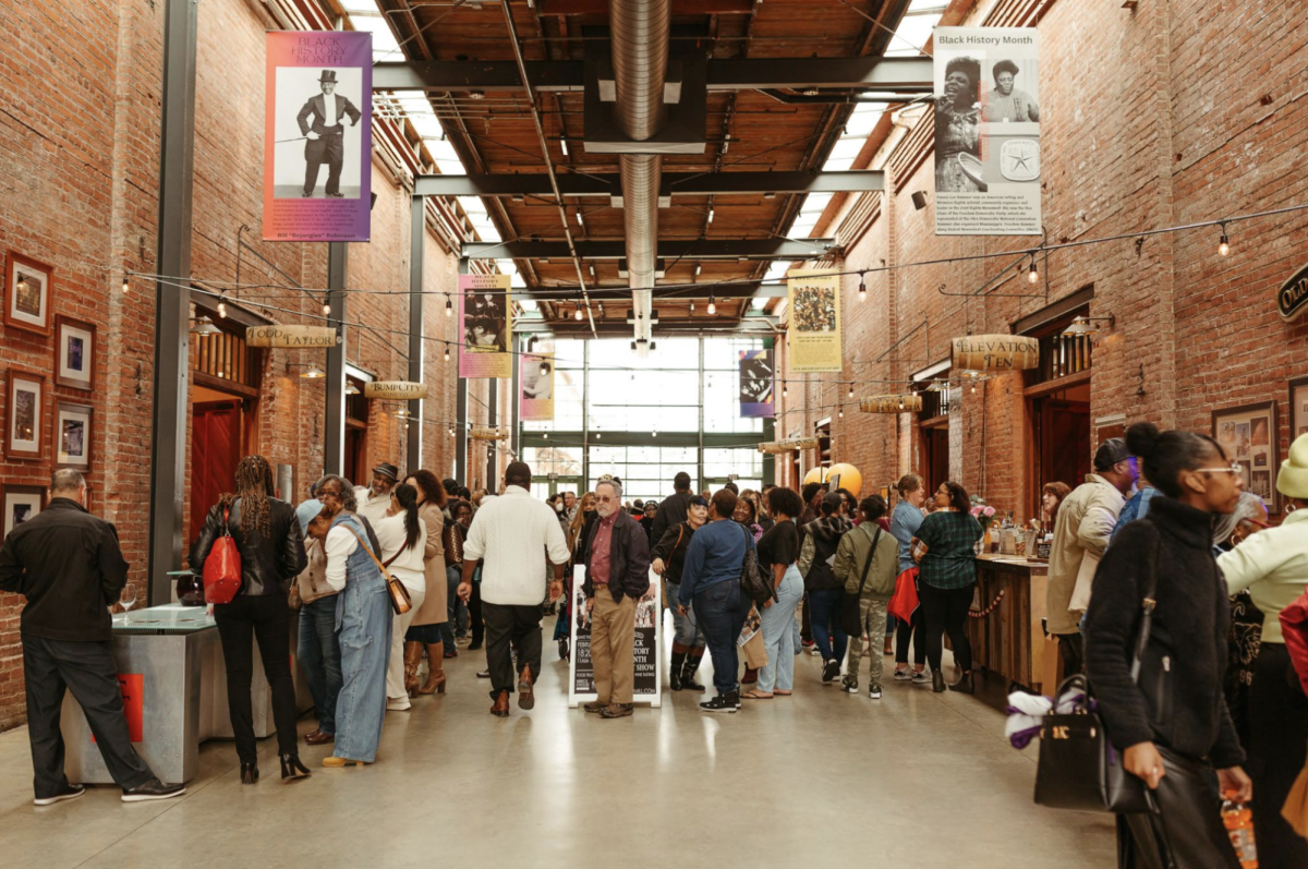 A crowd of people peruse wine tasting tables inside the Old Sugar Mill during the Black History Month Art Show Feb. 18, 2024. The Old Sugar Mill hosts 14 local wineries to emphasize a “farm-to-glass” concept.