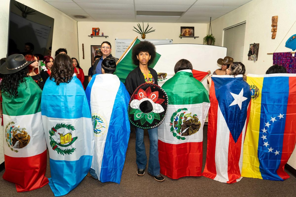 Jamarie Crawford poses with Latino country flags in Casa De Espanol classroom March 22, 2025. Crawford created his “Latinos Unidos” photoshoot to demonstrate Latino resilience. (Photo Courtesy of Ramon Rodriguez) 