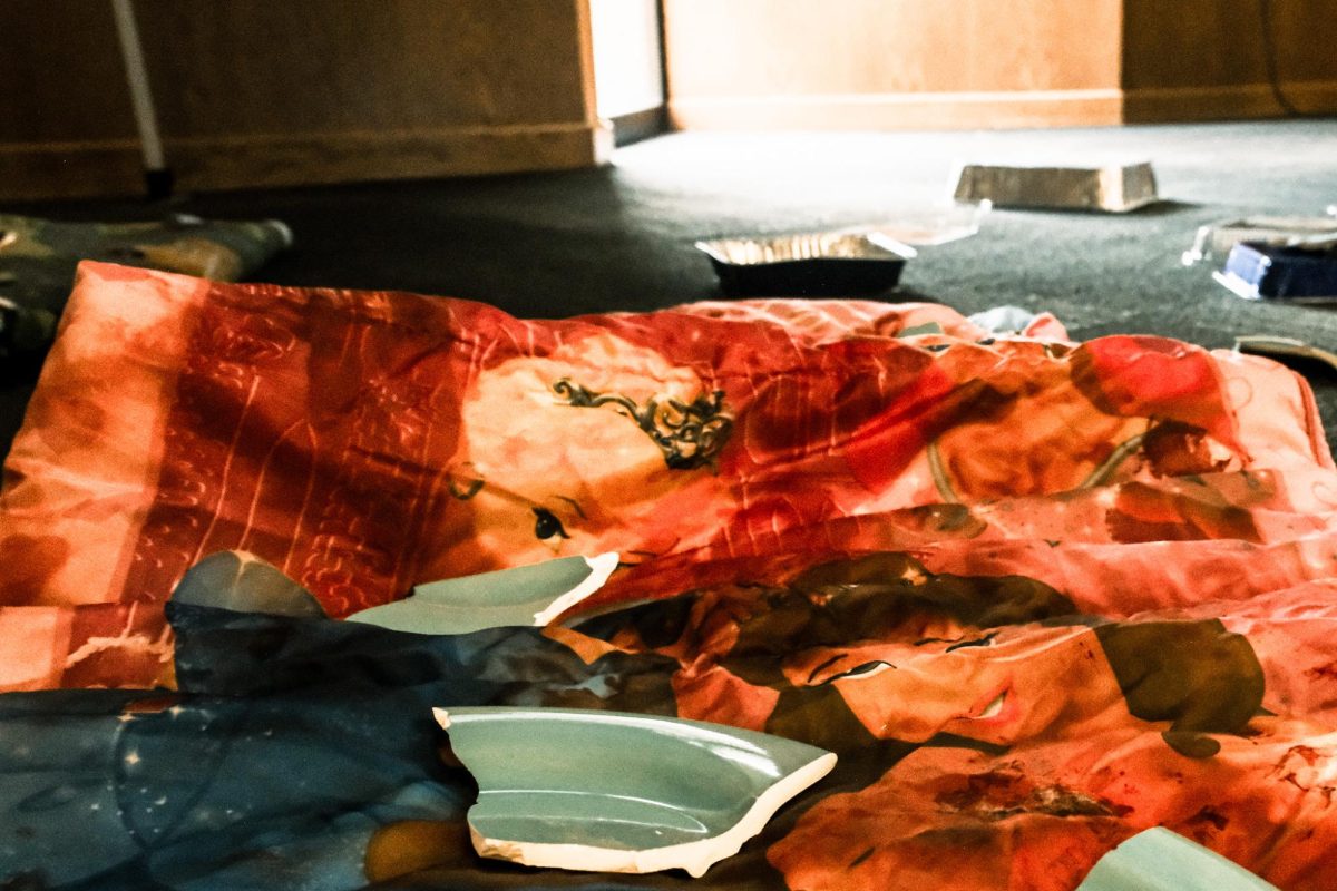 A child’s stained comforter is strewn with shards of plates at the “Step Into Gaza” exhibit at the Student Union’s Summit room, Oct. 7, 2025. The comforter was meant to represent belongings of children left behind in Gaza. 