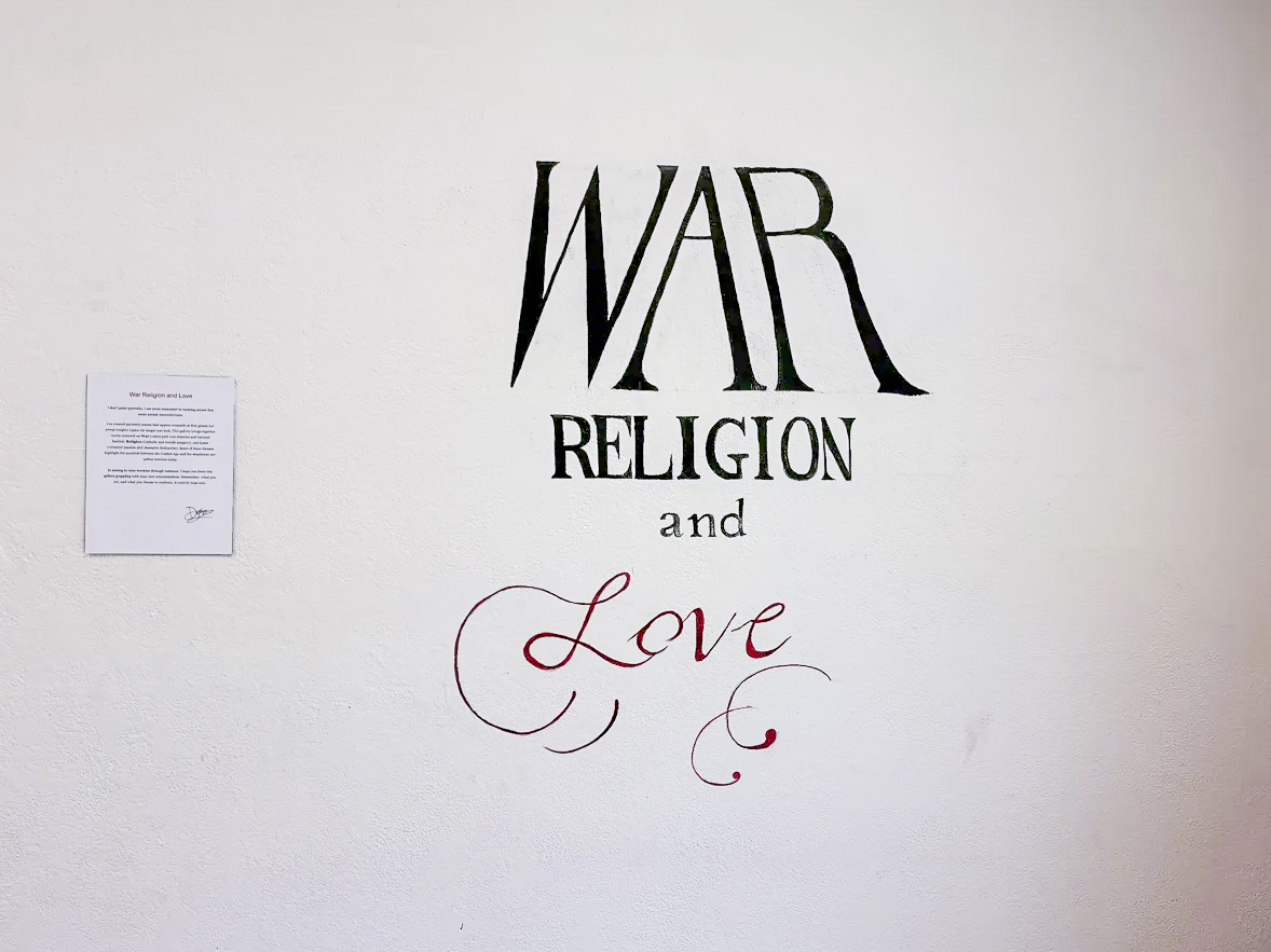 The entrance wall of third-year fine arts major Desiree Thomas’ solo exhibition at Sacramento State’s R.W. and Joyce Witt Gallery sets the tone on Thursday, April 2, 2026. Thomas said she wants visitors to leave grappling with their own interpretations of war, religion and love.