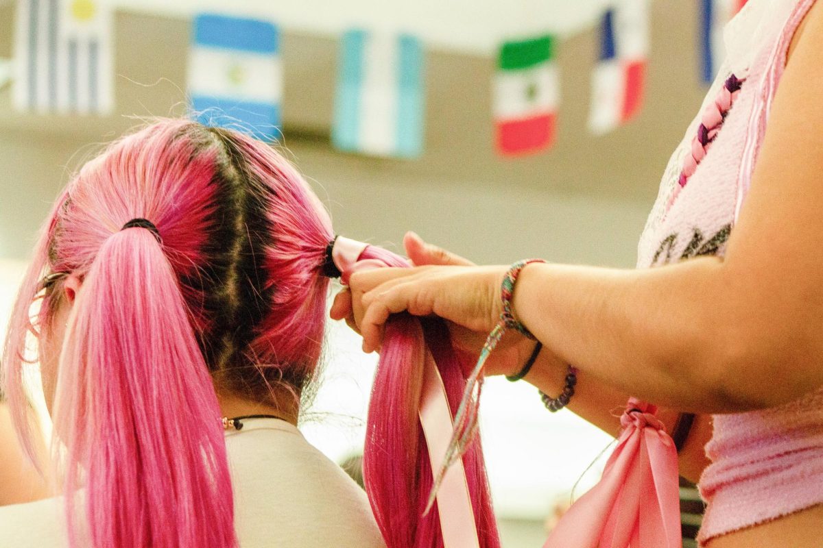 Elizah Hernandez, a fifth-year biology major, gets her hair braided in tranzas style at the “Braids not Raids” event Wednesday, April 29, 2026. In support of immigrant justice, she spent time with the braiders and other participants in casual conversation. 